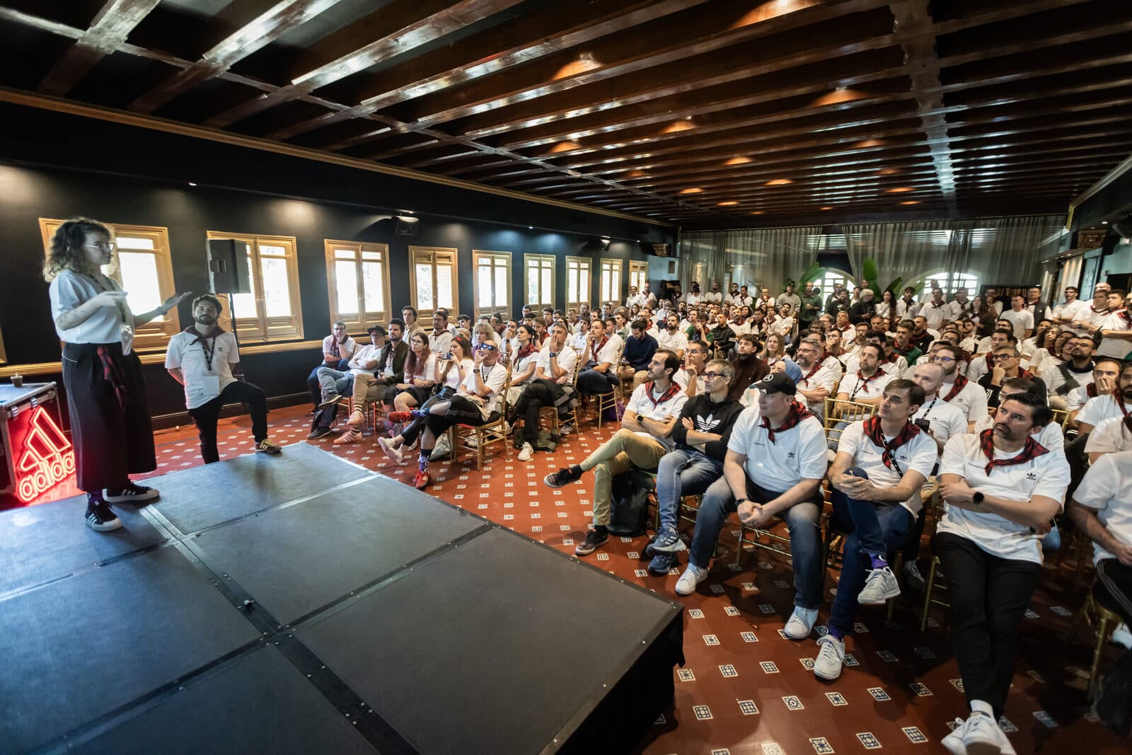 Ponente en escenario ante un auditorio lleno en un congreso corporativo en El Cachirulo